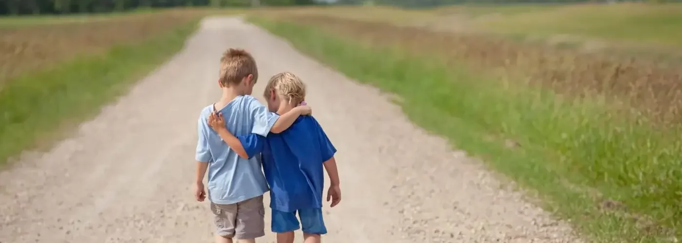 two caucasian boys walking down a country road
